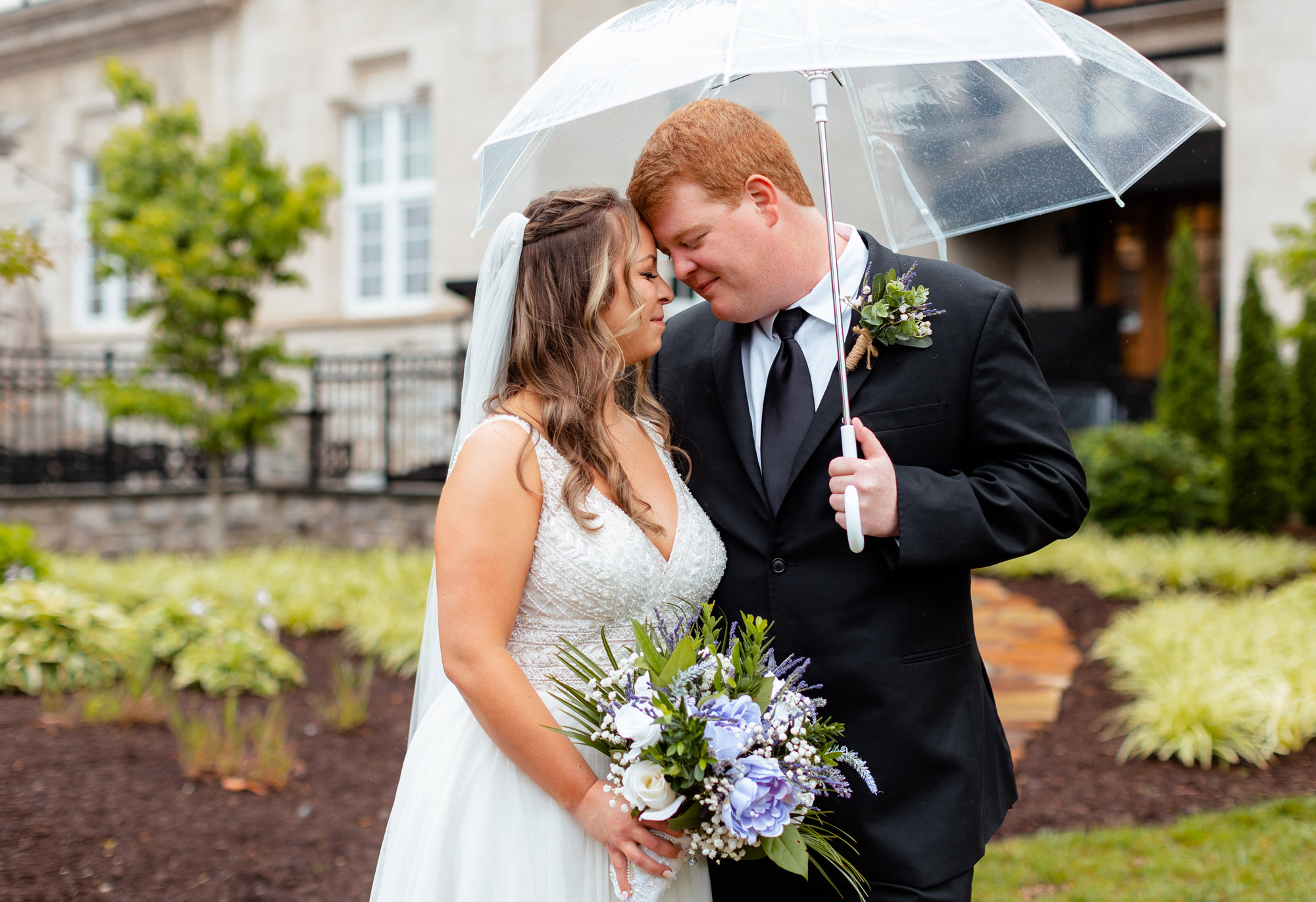 Couple under umbrella for wedding day photos