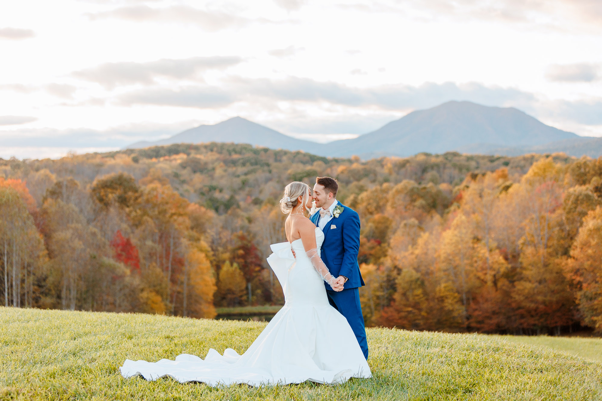 A bride and groom kissing in front of mountains