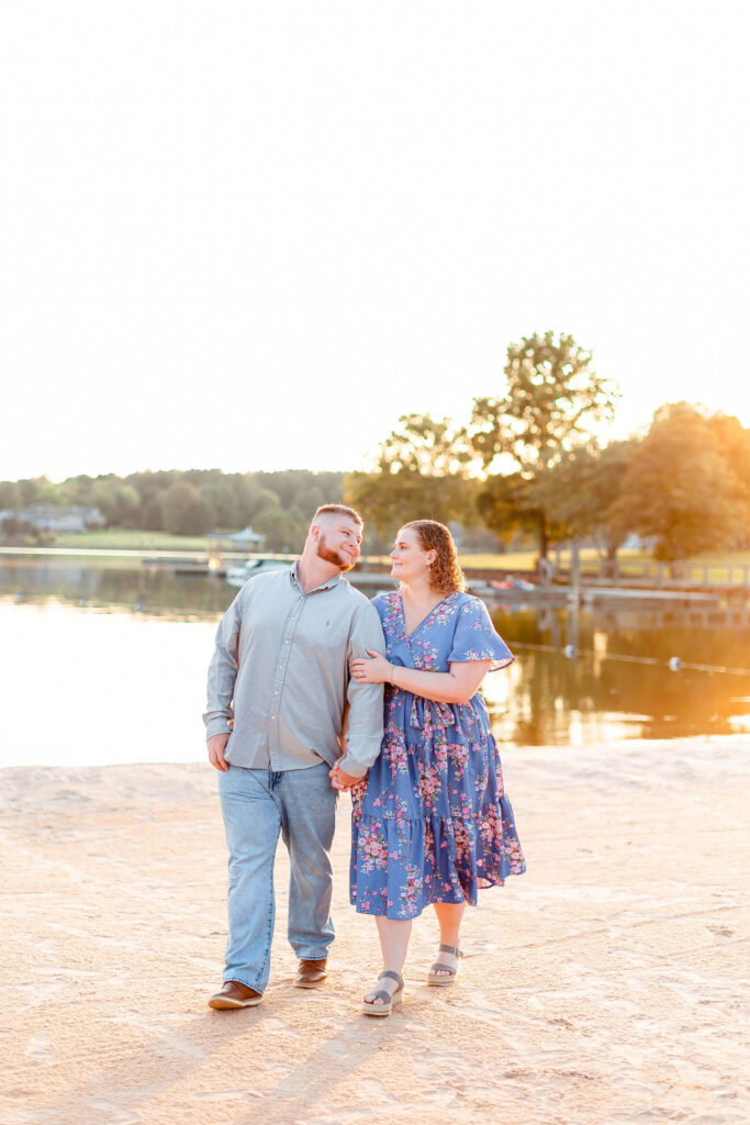 A happy couple share a sunset stroll by the water in a blue dress and button down